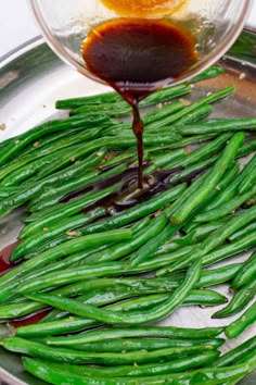 green beans being cooked in a pan with sauce