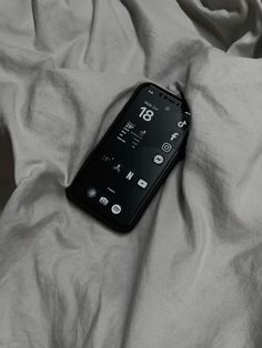 a cell phone laying on top of a bed covered in white sheets and linens