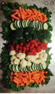 vegetables laid out on top of each other in the shape of a rectangle, with cucumbers, carrots, broccoli and cauliflower