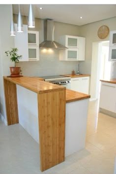 a kitchen with white cabinets and wooden counter tops in front of a stove top oven