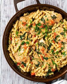 a skillet filled with pasta, meat and vegetables