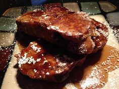 two pieces of french toast covered in powdered sugar on top of a cutting board