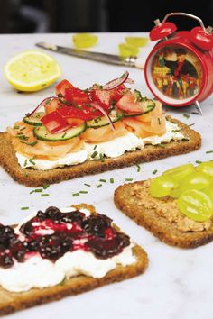 three slices of bread with various toppings on them and a clock in the background