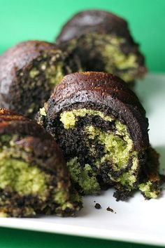 chocolate and green cake roll on a white plate with one cut in half to show the inside