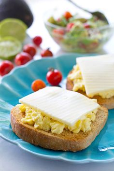 two pieces of bread with eggs and cheese on them are sitting on a blue plate