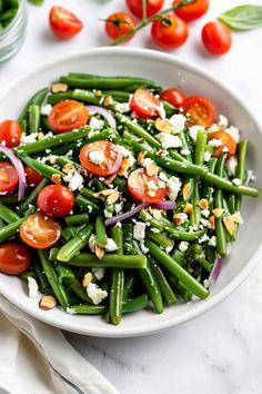 a white bowl filled with green beans and tomatoes