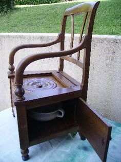 an old wooden chair sitting on top of a table next to a cement wall and green grass