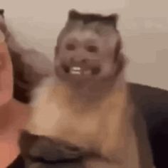 two people are smiling and one has a cat on his shoulder while the other is holding something