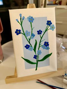 an easel with a painting of blue flowers on it