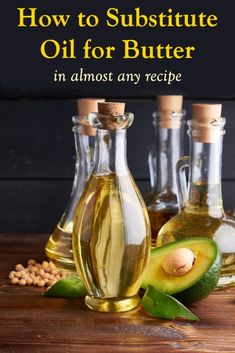 three bottles filled with oil and an avocado cut in half on top of a wooden table