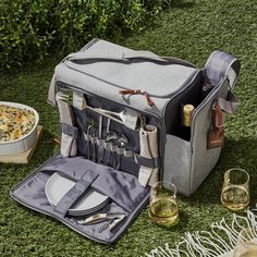 an open picnic bag with utensils and silverware in it on the grass