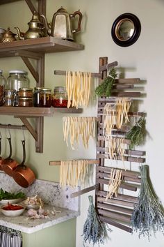 pasta hanging on the wall in a kitchen with other cooking utensils and ingredients