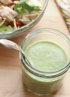 a salad in a jar with a spoon next to it on a wooden cutting board