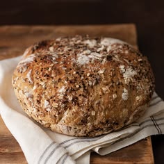 a loaf of bread sitting on top of a wooden cutting board next to a white towel
