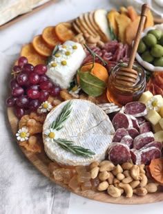 a platter with cheese, crackers, fruit and nuts on it is shown