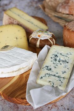several different types of cheese on a wooden plate