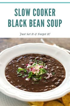 a white bowl filled with black bean soup next to chips