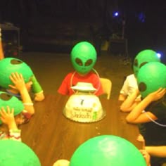 several children with green alien heads sitting around a table