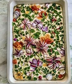 a casserole dish with flowers and leaves on it sitting on a marble counter top