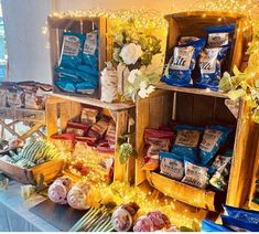 a table topped with lots of food and bags of chips next to each other on top of a wooden shelf
