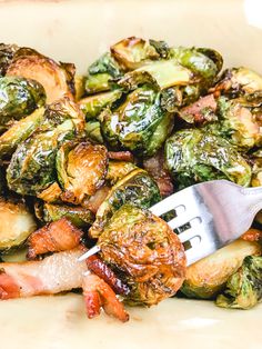 brussel sprouts and bacon are in a white bowl with a fork