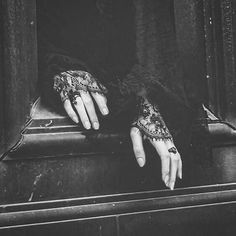 a woman's hands with black lace on them are resting on a metal box