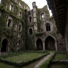 an old building with ivy growing all over it's walls and windows, surrounded by grass