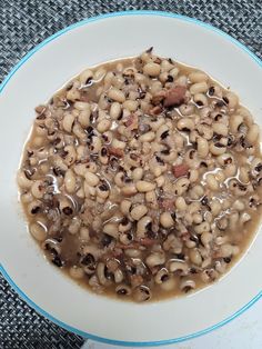 a white plate topped with beans covered in gravy on top of a blue and white table cloth