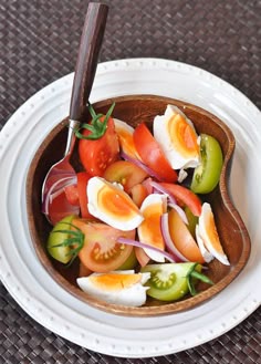 a wooden bowl filled with sliced up tomatoes and hard boiled eggs on top of onions