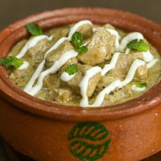 a clay pot filled with food and garnished with green leafy toppings