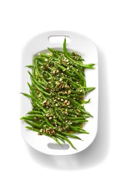green beans with sesame seeds and seasoning on a white platter, viewed from above