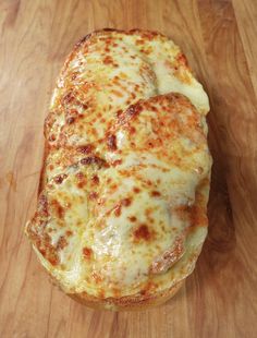 a cheesy pizza sitting on top of a wooden cutting board