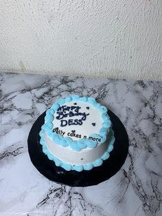 a blue and white birthday cake sitting on top of a marble counter next to a wall