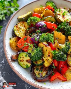 a white bowl filled with lots of different types of vegetables on top of a table