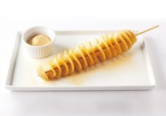 a white plate topped with food and a wooden skewer filled with something yellow