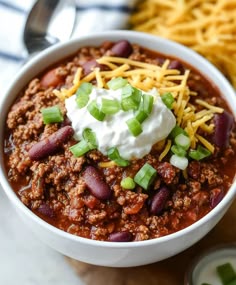 a white bowl filled with chili and sour cream