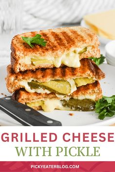grilled cheese sandwich with pickles and parsley on a white plate next to a fork