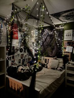 an unmade bed with lights strung from the ceiling and pictures on the wall behind it