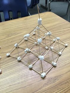 a wooden table topped with an object made out of sticks and white balls on top of it