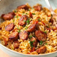 a bowl filled with rice and sausage on top of a table