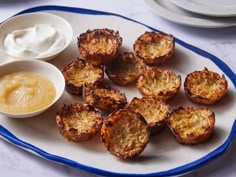 a white plate topped with mini potatoes next to a bowl of mayonnaise and dip