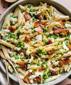 a bowl filled with pasta, peas and bacon