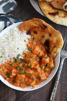 a white plate topped with rice and chicken next to naan bread on a wooden table