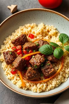 A bowl of flavorful couscous topped with tender beef cubes, garnished with cherry tomatoes, fresh herbs, and colorful vegetable strips.