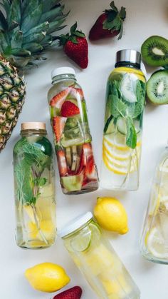several different types of fruit in mason jars with strawberries, kiwis and lemons