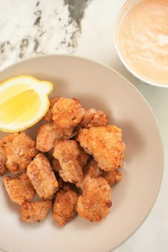 a white plate topped with tater tots next to a bowl of dipping sauce