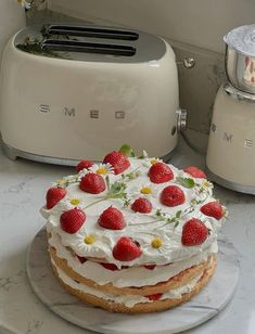 a cake sitting on top of a white plate next to a toaster and knife