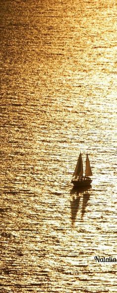 a small boat floating on top of a body of water under a yellow sunlit sky