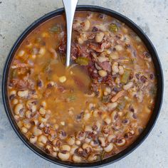 a black bowl filled with beans and meat soup on top of a gray countertop