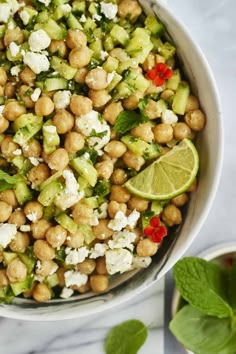 a white bowl filled with chickpeas, cucumber and feta cheese